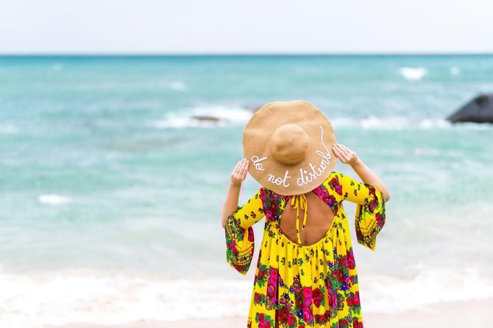 Woman on beach in yellow dress wearing hat-1