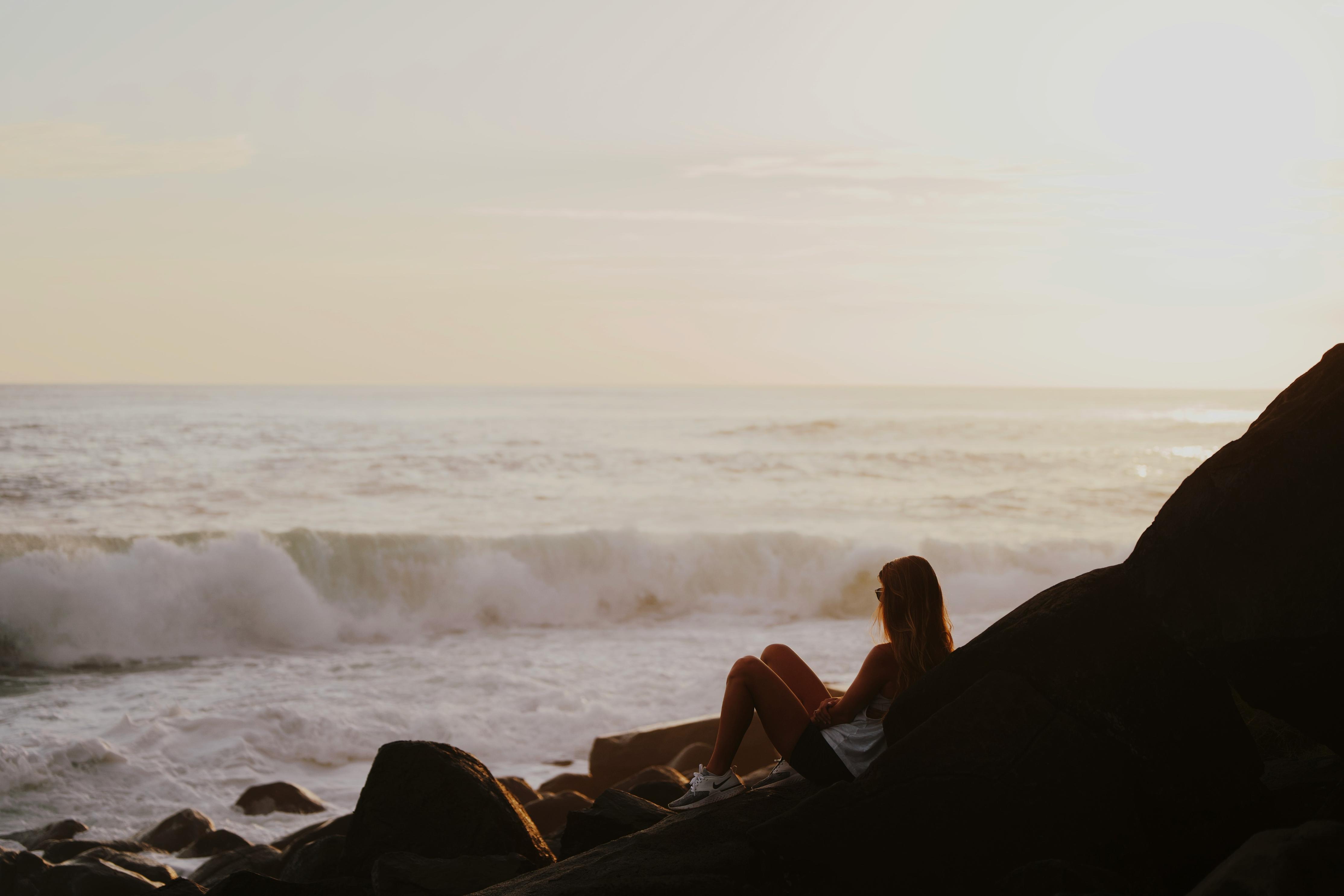 Woman watching the ocean from the rocks along the shore